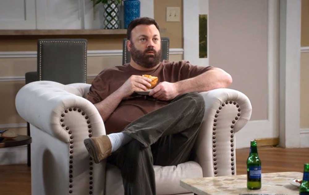 Chris Roach in Kevin Can Wait on the sofa